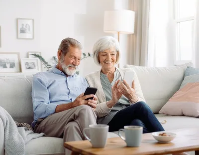 Senior Couple Using Smartphones Together on Sofa