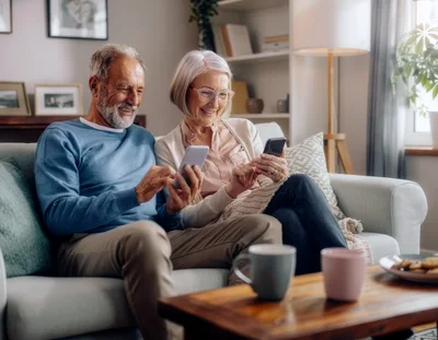 Senior Couple Using Smartphones Together on Sofa