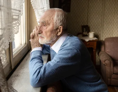 Elderly Man Looking Out A Window