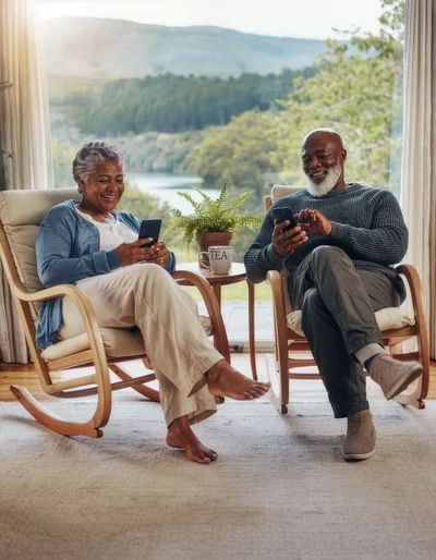 Senior Couple Relaxing In Rocking Chairs Using Smartphones