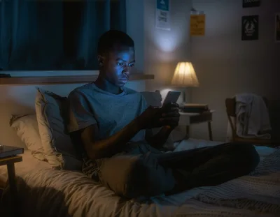 Young Man Using Smartphone In Bed At Night
