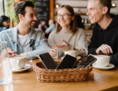 Friends Socializing at a Cafe with Phones in Basket