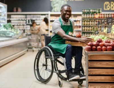 Smiling Grocery Store Employee In Wheelchair Organizing Apples