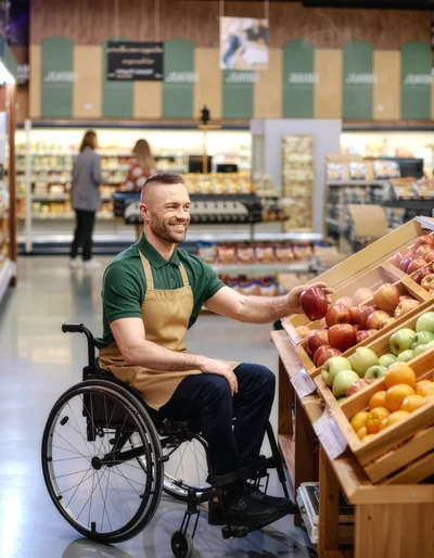 Smiling Grocery Store Employee In Wheelchair Organizing Apples