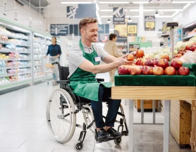 Smiling Grocery Store Employee In Wheelchair Arranging Apples