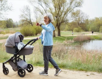 Senior Woman Walking With Baby Stroller In Park