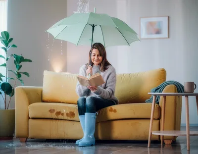 Mature Woman Reading Under Umbrella During Indoor Leak