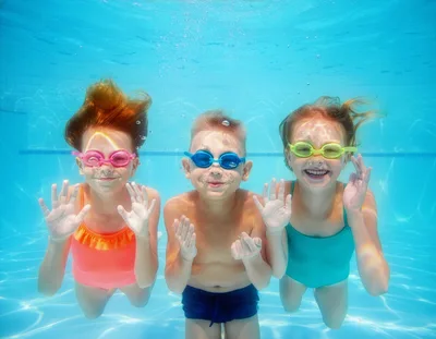 Three Children Swimming Underwater In A Pool