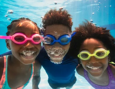 Three Children Swimming Underwater In A Pool