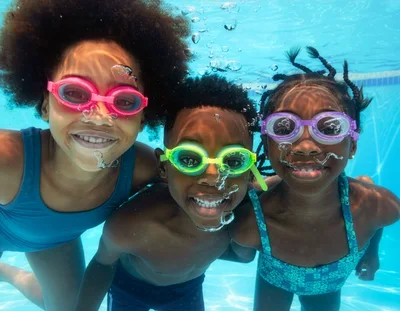 Three Children Swimming Underwater In A Pool