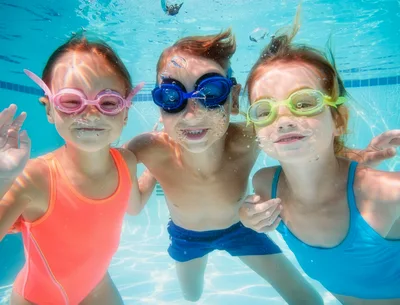 Three Children Swimming Underwater In A Pool