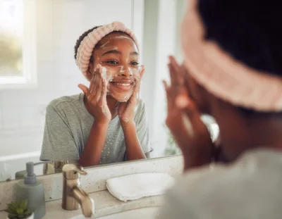 Young Woman Washing Face With Cleanser In Bathroom