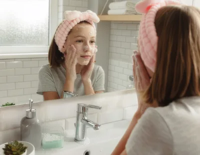 Young Girl Washing Face With Cleanser In Bathroom