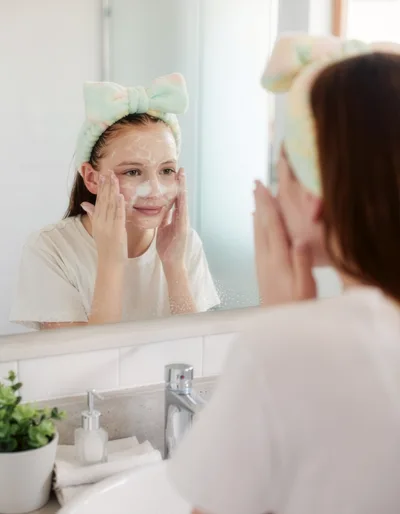 Young Girl Washing Face With Cleanser In Bathroom