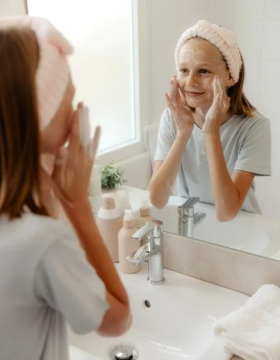 Young Girl Washing Face with Cleanser in Bathroom