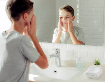 Young Boy Washing Face With Soap In Bathroom Mirror