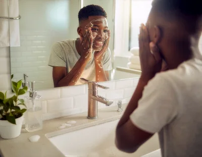 Young Man Washing Face With Soap In Bathroom