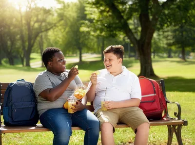 Two Boys Eating Snacks on a Park Bench