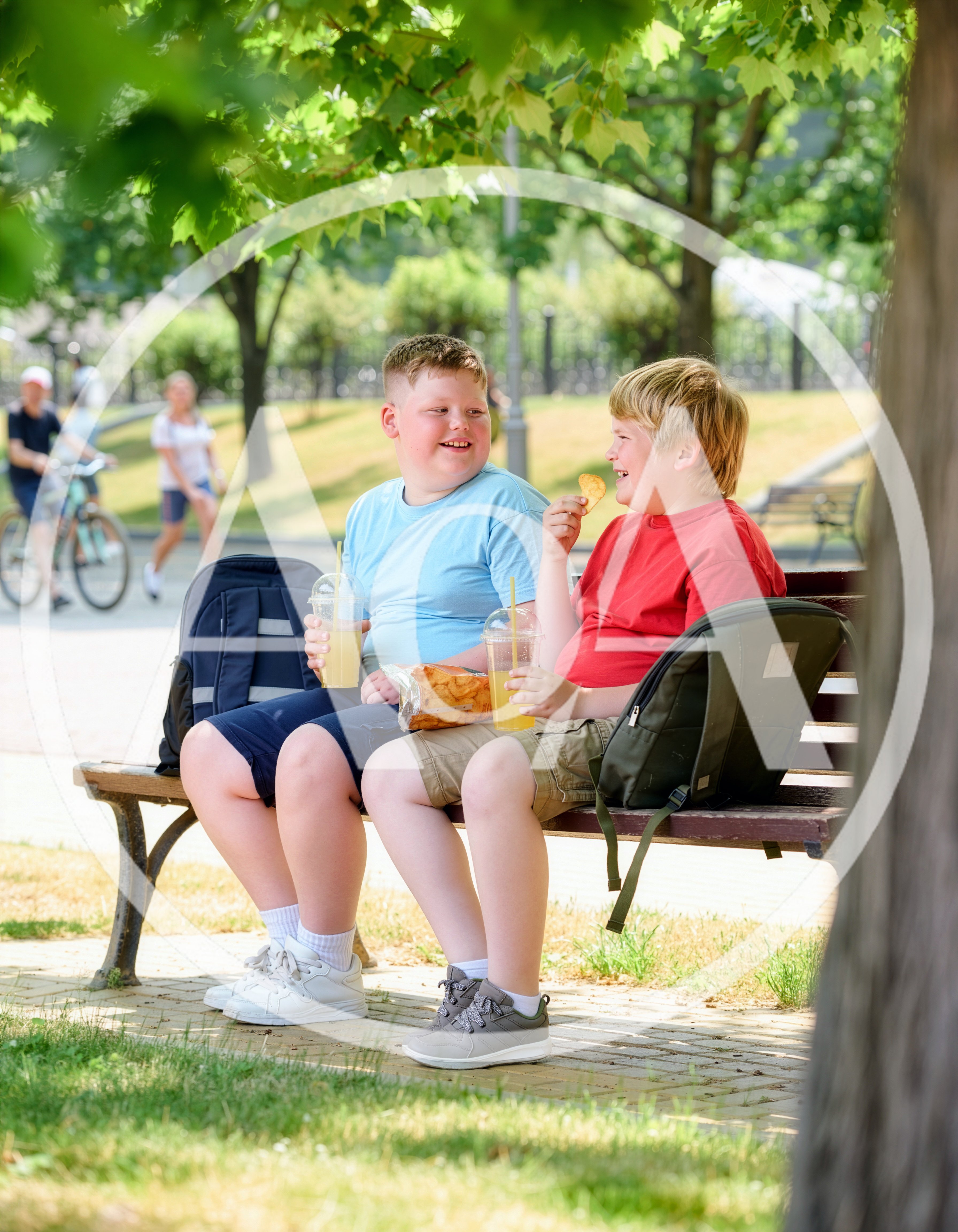 Two Boys Eating Snacks and Drinking Juice on Park Bench