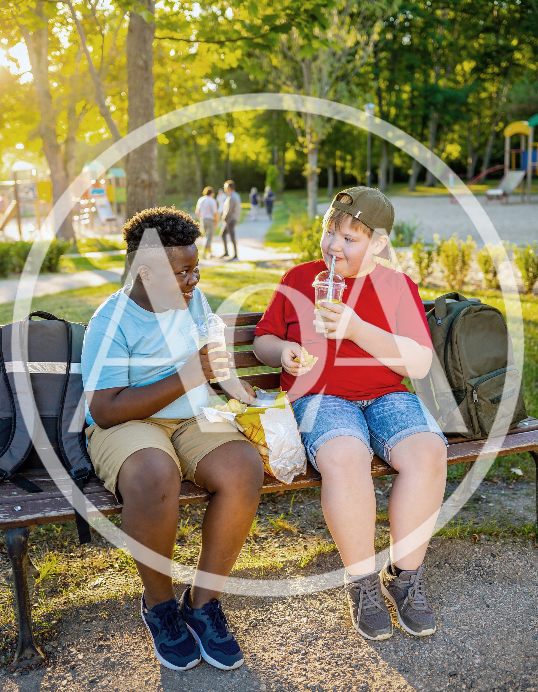 Two Boys Eating Snacks and Drinking Lemonade on Park Bench