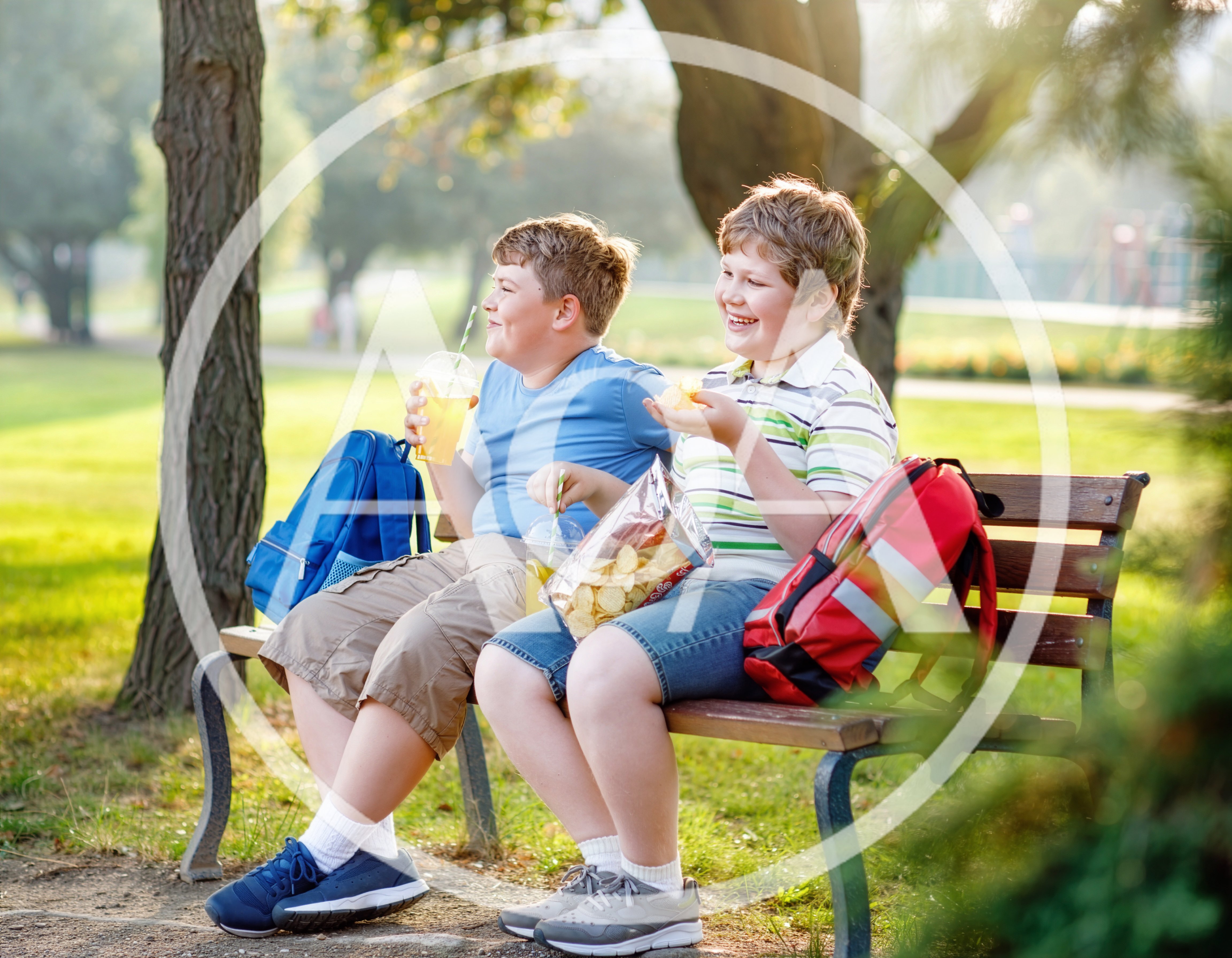Two Boys Eating Snacks on a Park Bench