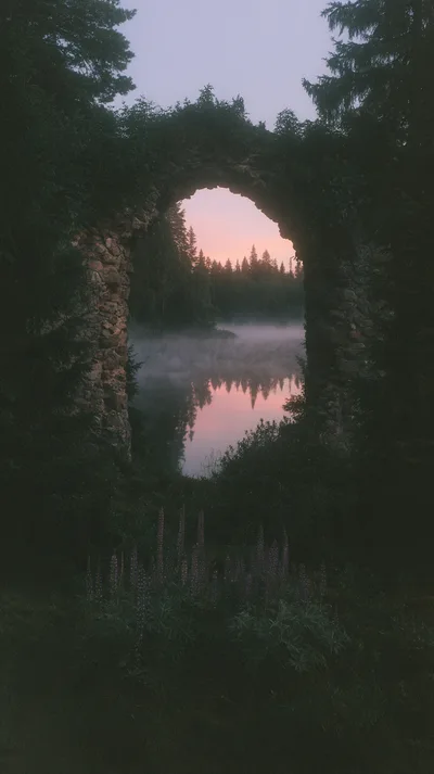 Stone Archway Overlooking A Misty Forest Lake At Sunset