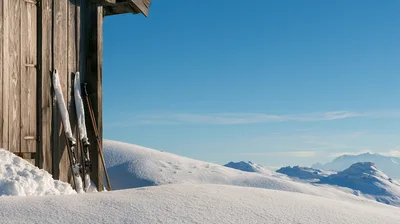 Vintage Wooden Skis Leaning Against A Rustic Alpine Hut