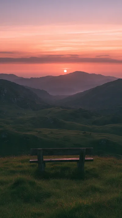 Wooden Bench Overlooking A Mountain Valley At Sunset