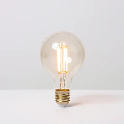 Glowing LED Filament Light Bulb On White Surface