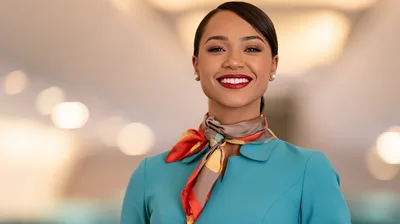 Smiling Flight Attendant Wearing Teal Uniform And Silk Scarf