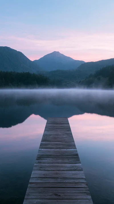Wooden Pier Extending Into A Misty Mountain Lake