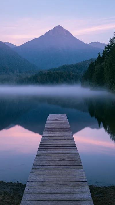 Wooden Pier Extending Into A Misty Mountain Lake