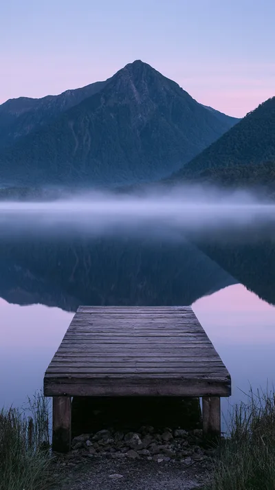 Wooden Pier Extending Into A Calm Misty Lake