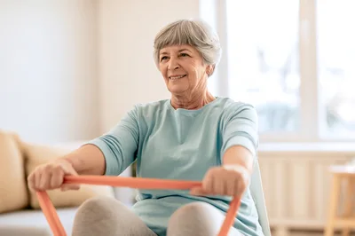 Senior Woman Exercising With Resistance Band At Home