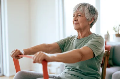 Senior Woman Exercising With Resistance Band At Home