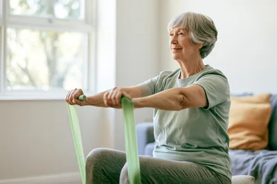 Senior Woman Exercising With Resistance Band At Home