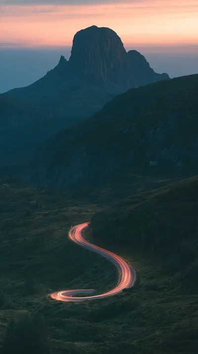 Winding Mountain Road With Car Light Trails At Dusk
