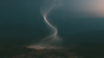 Small Dust Devil Swirling Over Dark Barren Landscape