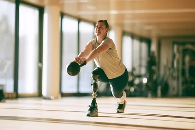 Woman With Prosthetic Leg Performing Kettlebell Lunge Exercise