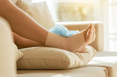 Injured Ankle Wrapped In Compression Bandage With Ice Pack