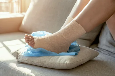 Person Resting An Injured Ankle On A Sofa