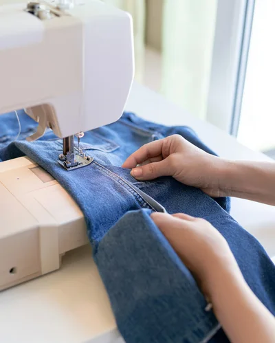 Person Sewing Denim Fabric With A Sewing Machine