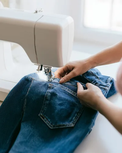 Person Sewing Denim Jeans On A Sewing Machine