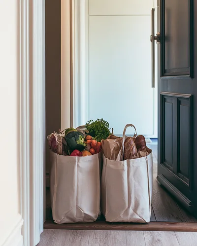 Two Canvas Grocery Bags Filled With Fresh Produce And Bread