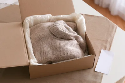 Beige Knitted Sweater Inside A Cardboard Shipping Box