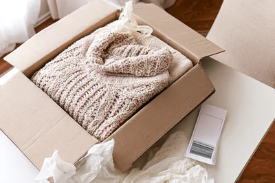 Beige Knitted Sweater Inside A Cardboard Shipping Box