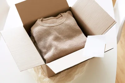 Beige Knitted Sweater Inside A Cardboard Shipping Box