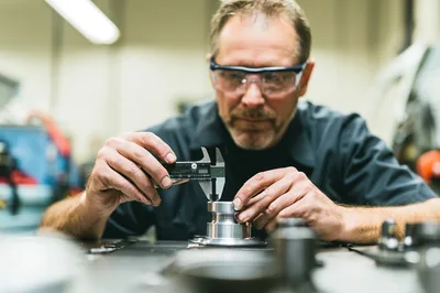 Machinist Measuring Metal Part With Digital Calipers