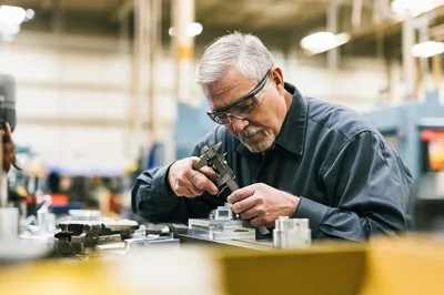Machinist Measuring Metal Part With Calipers