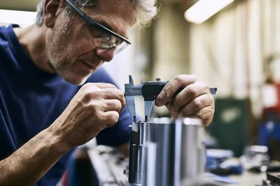 Machinist Measuring Metal Component With Digital Calipers